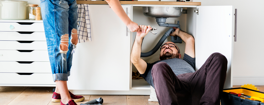 Couple repairing a leaking sink in the kitchen