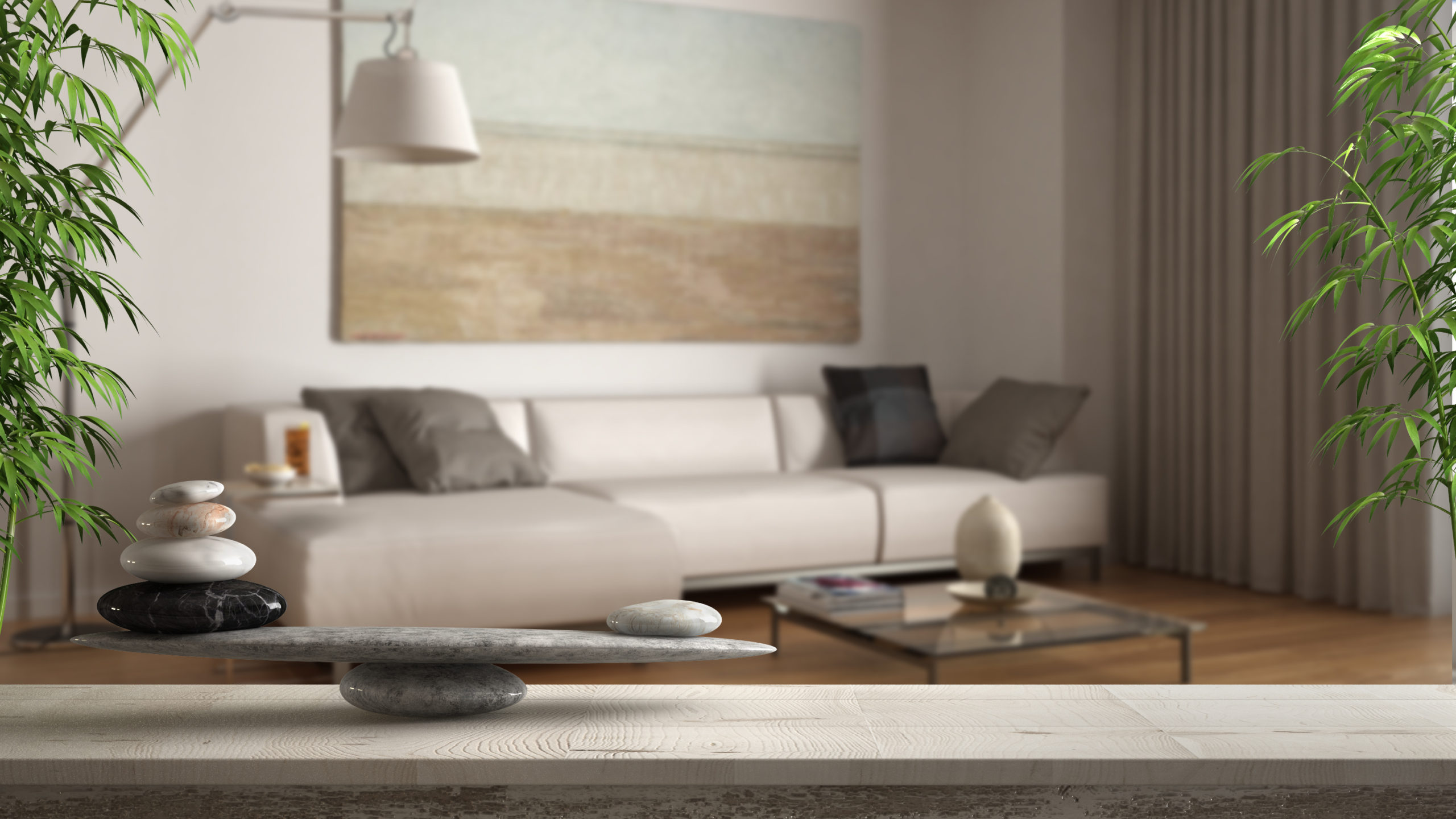 Wooden vintage table or shelf with stone balance, over blurred classic living room with sofa and floor lamp, feng shui, zen concept architecture interior design