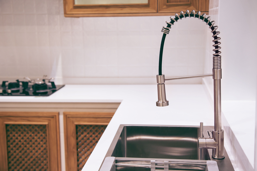 Designed kitchen with glossy countertop and stainless steel faucet