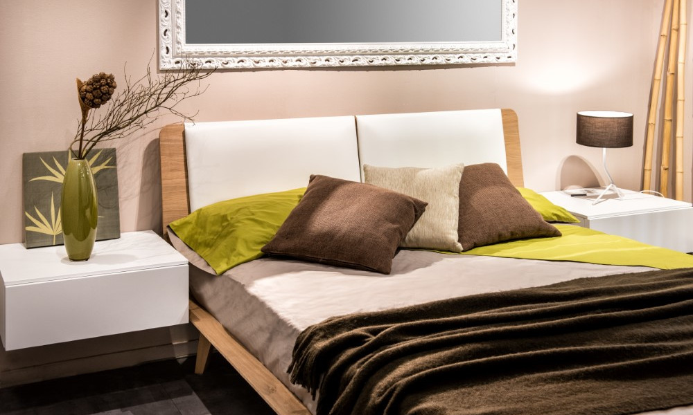 Bedroom interior with four pillows on bed and mirror on wall